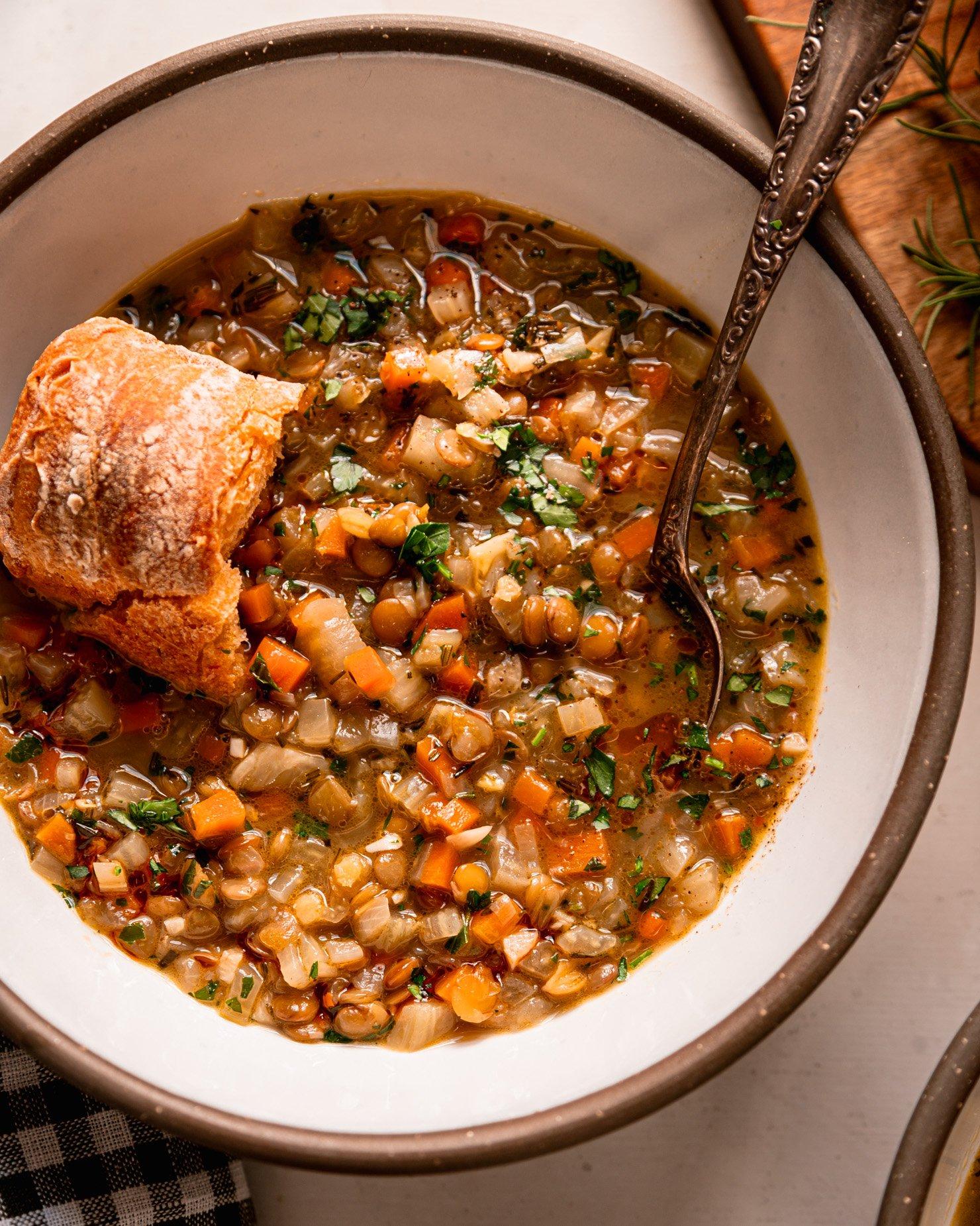 Bowl of lentil soup with fresh herbs and a side of crusty bread