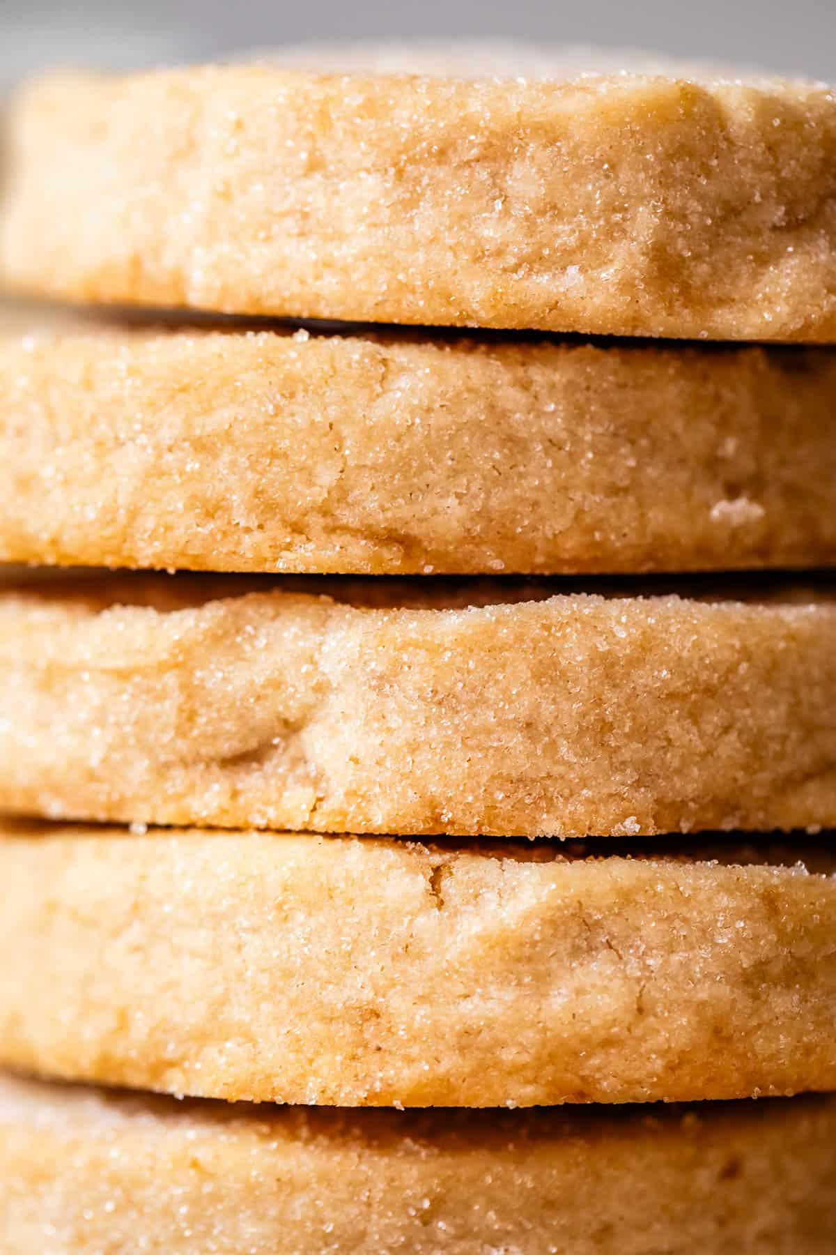 close-up of golden brown shortbread cookies stacked on a wire rack with crumbs, soft focus