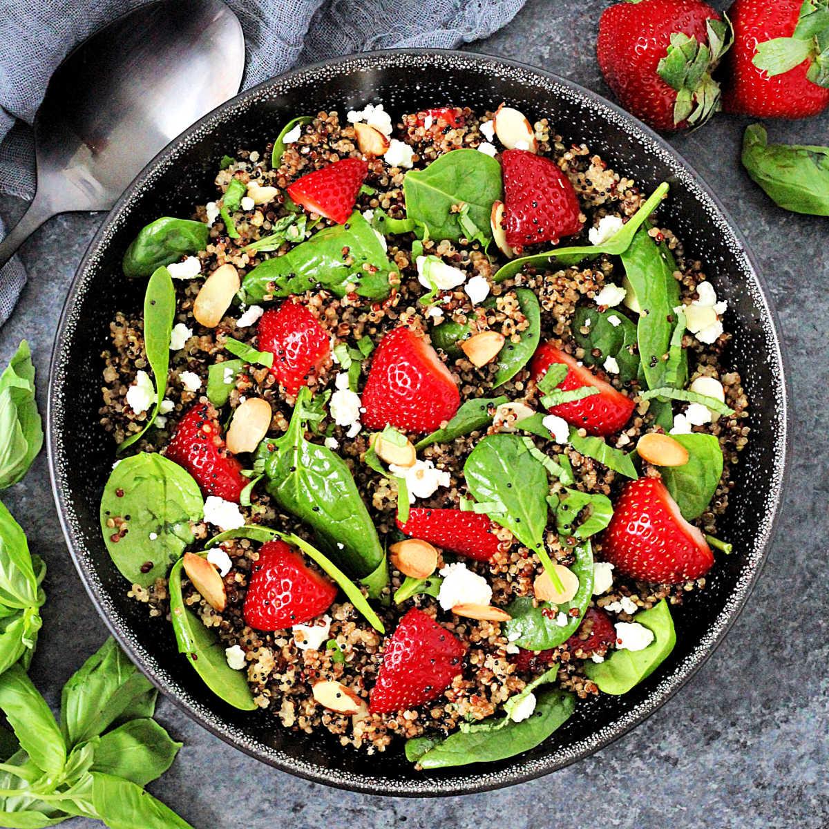 aerial view of strawberry spinach quinoa salad on a rustic wooden table