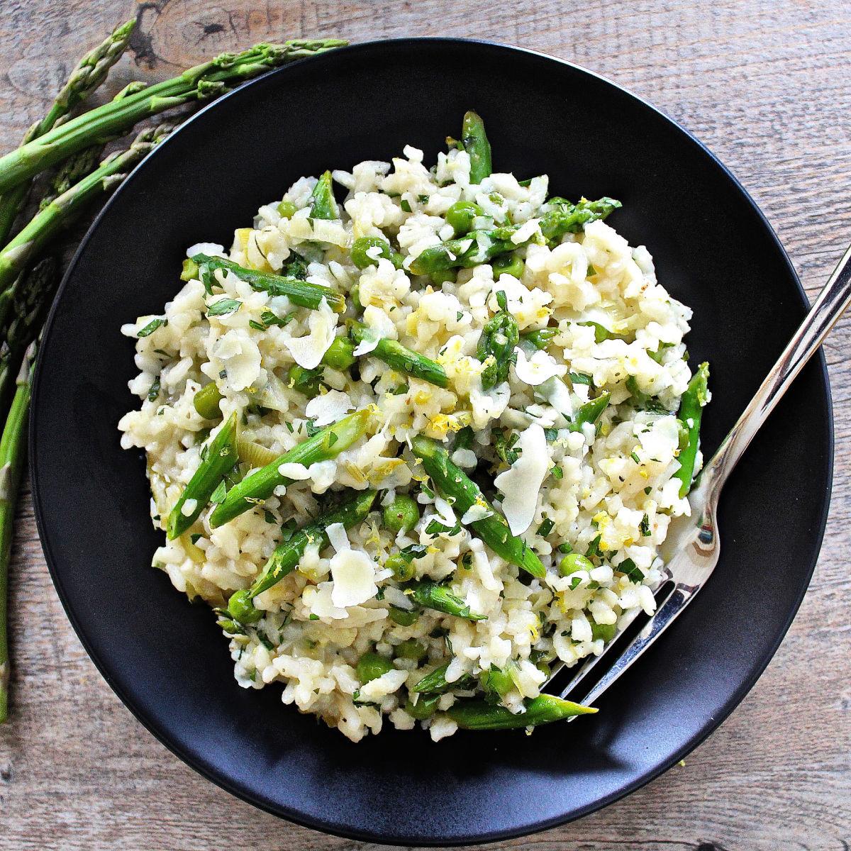 A person plating the asparagus risotto and garnishing it with lemon zest and herbs