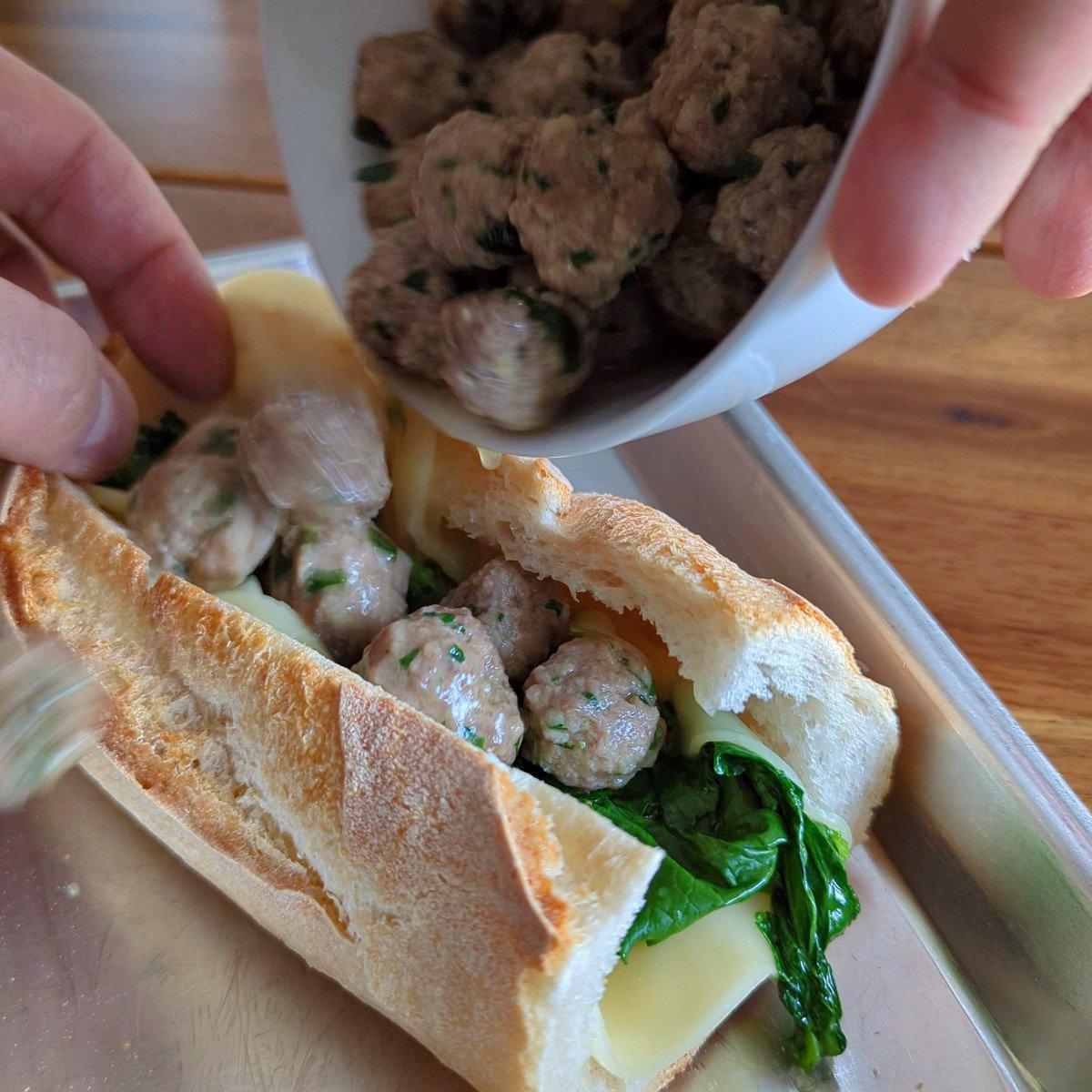 Close-up of a person's hands assembling the Italian Wedding Soup Sandwich