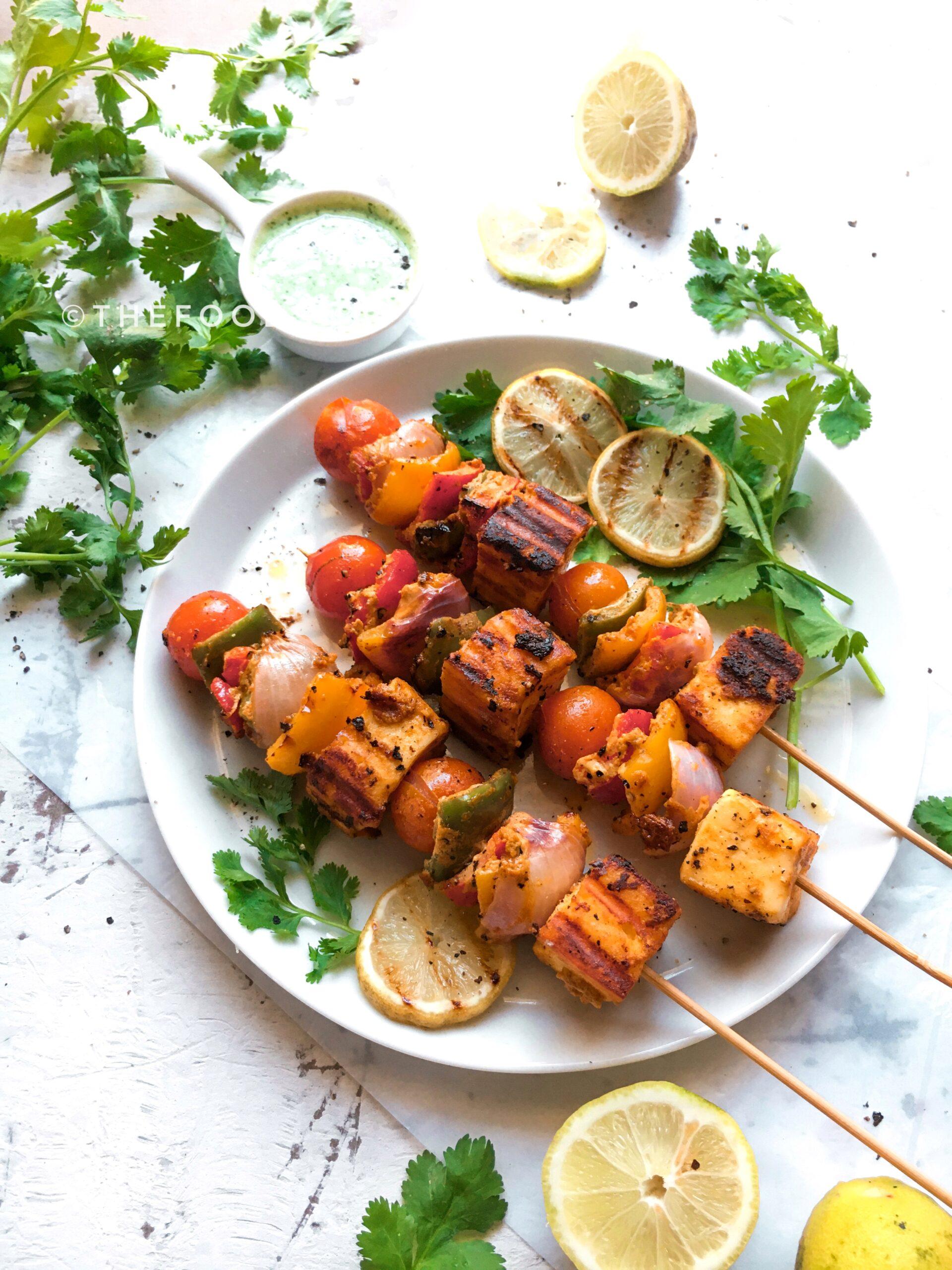 A plate of spicy jalapeño paneer tikka, garnished with cilantro and lemon wedges