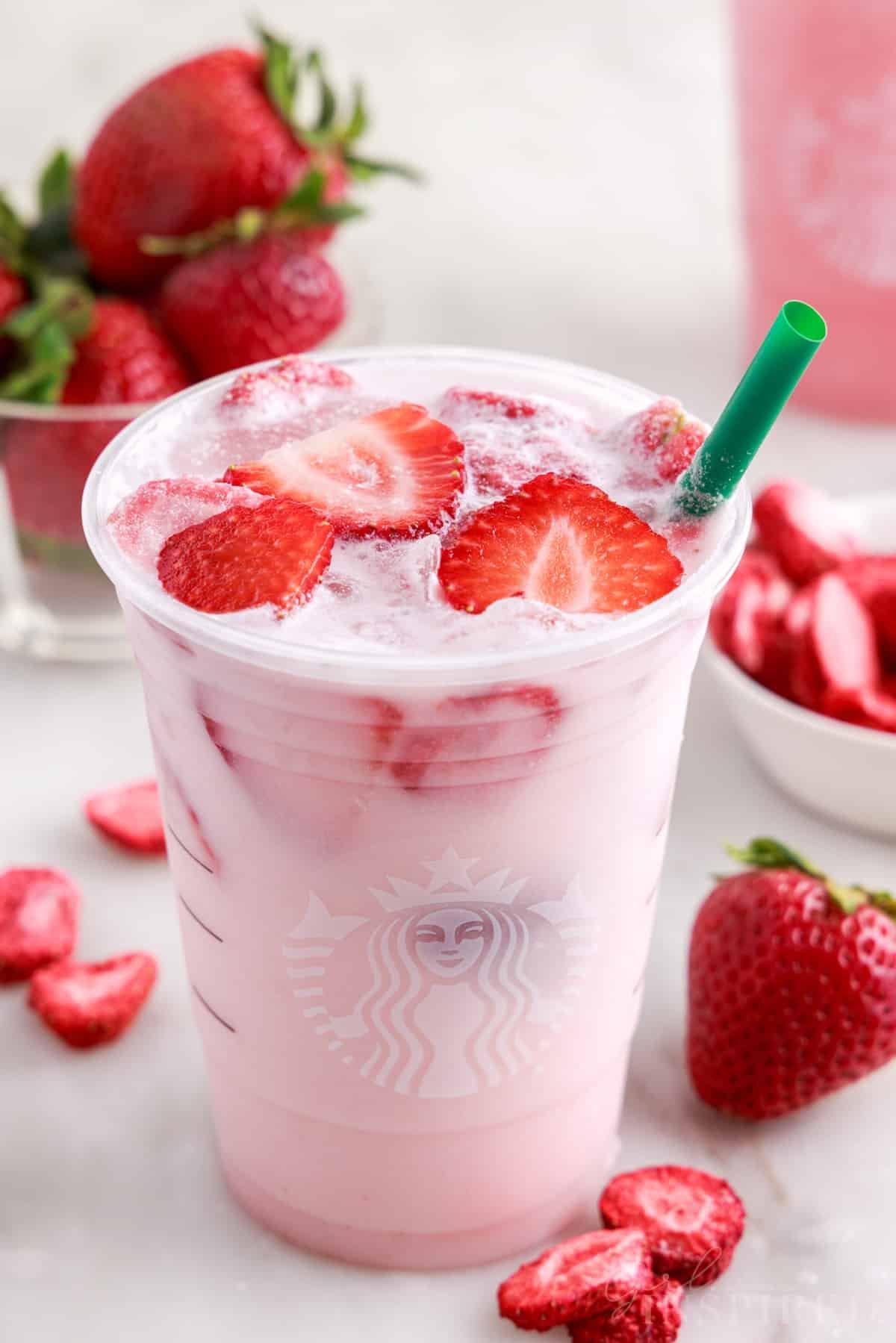 Close-up shot of a vibrant pink Strawberry Spinach Refresher in a glass, garnished with fresh strawberries and mint