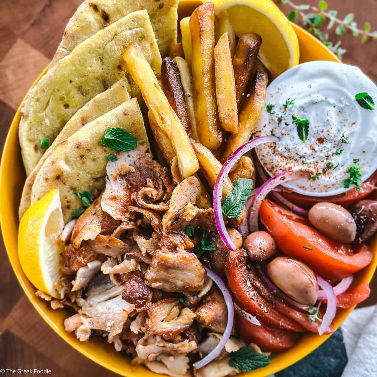 A vibrant, colorful bowl of gyro-flavored salsa, garnished with fresh herbs and a side of pita bread.