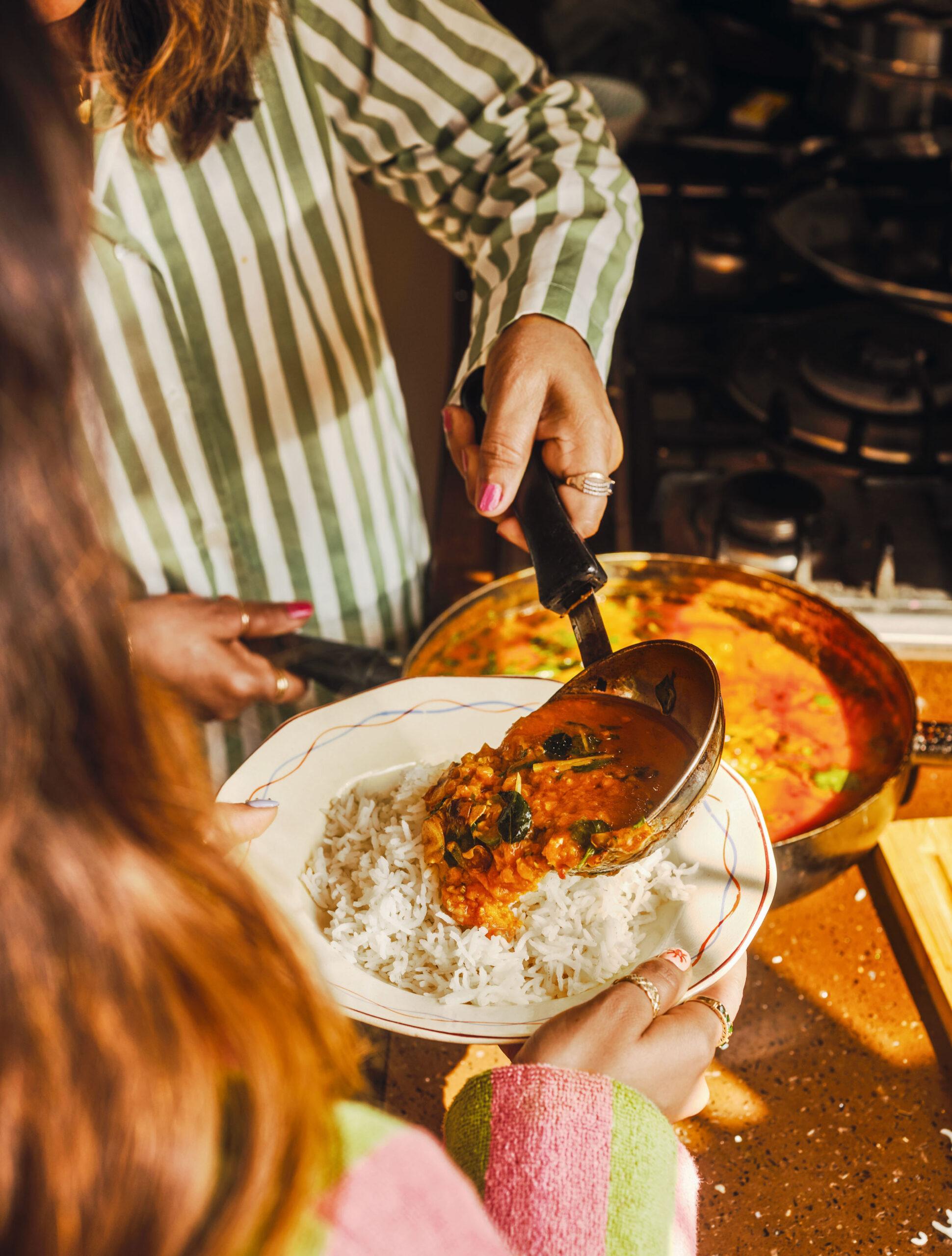 A person happily stirring a pot of dal