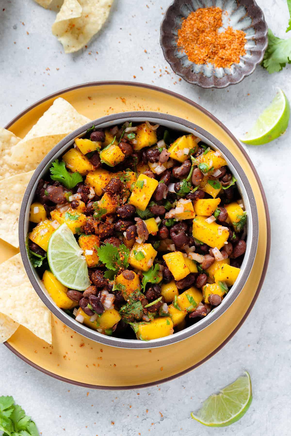 vibrant black bean salsa with chunks of mango and pineapple, garnished with cilantro and lime