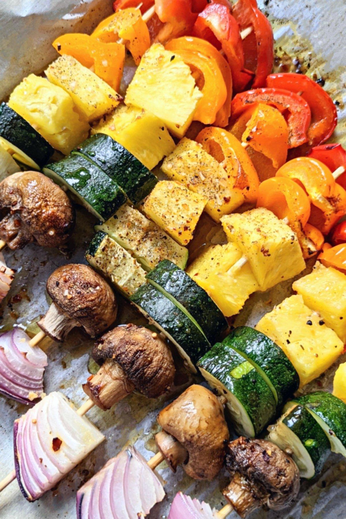 Close-up shot of colorful roasted vegetable and kötbullar skewers on a baking sheet
