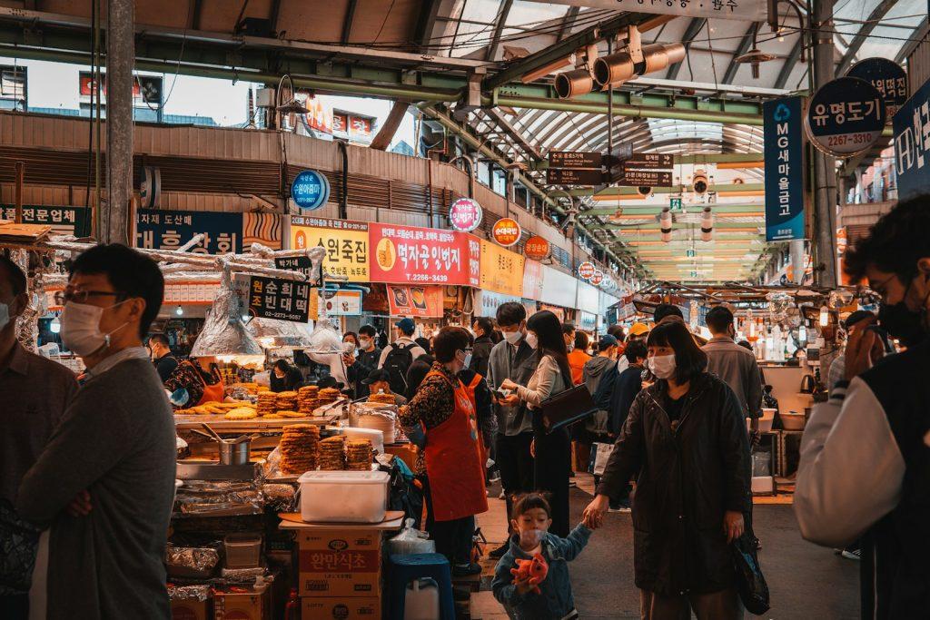 Image of a bustling street food market in Seoul, South Korea, with various food vendors and happy customers
