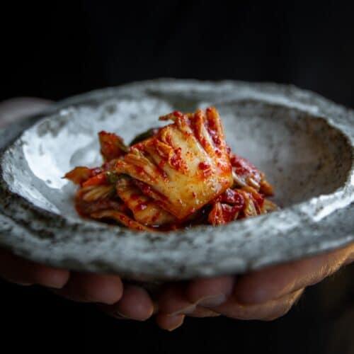 close-up shot of kimchi being added to a pot of chili