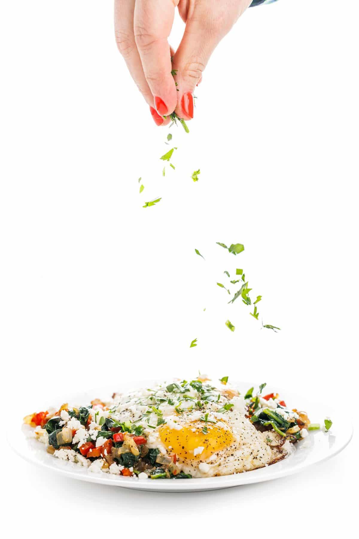 A person enjoying a plate of sautéed eggs with vegetables