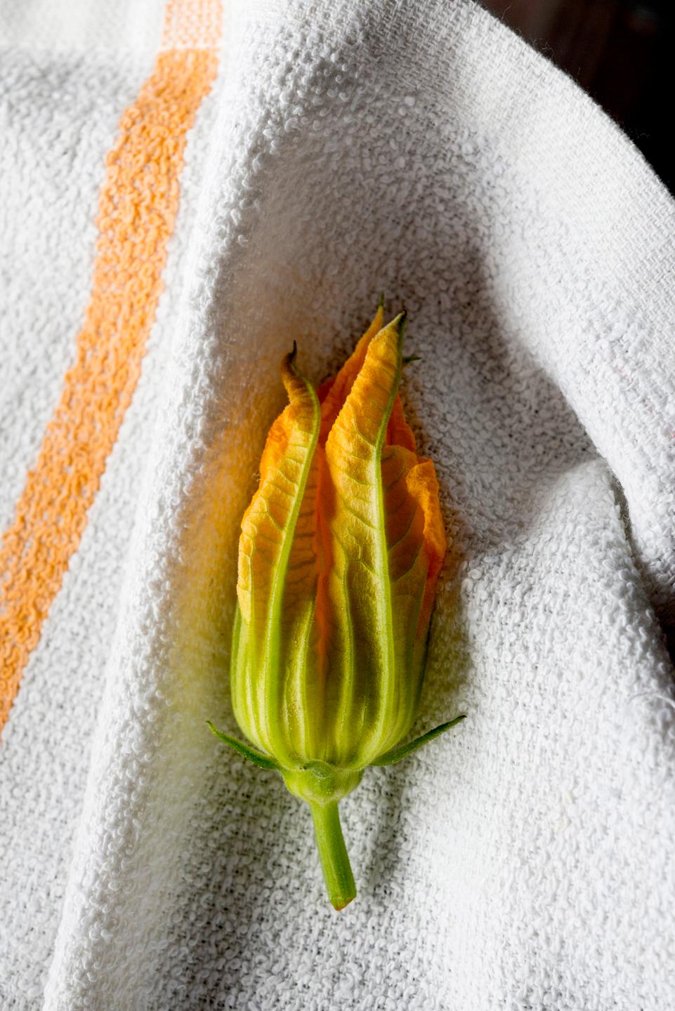 a close-up of vibrant orange squash blossoms at a farmer's market