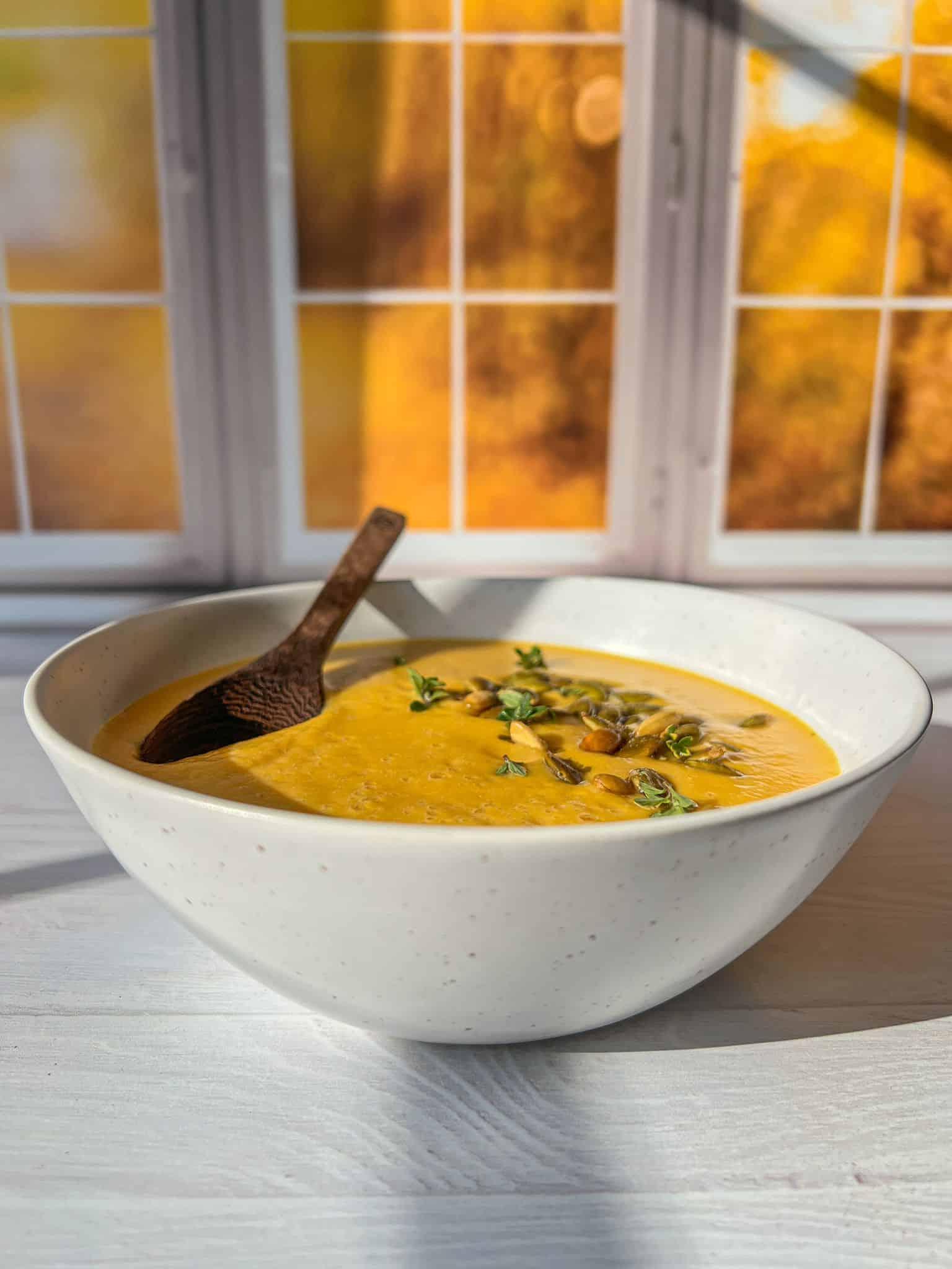 garnished creamy pumpkin and butternut squash soup on a wooden table