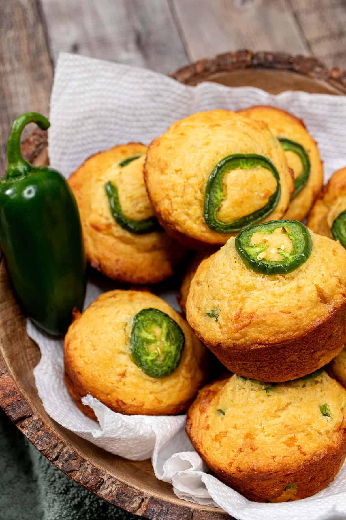 close up shot of a basket filled with basil jalapeno cornbread muffins