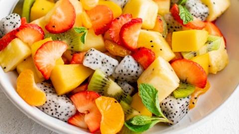 Person enjoying a tropical fruit salad on a beach