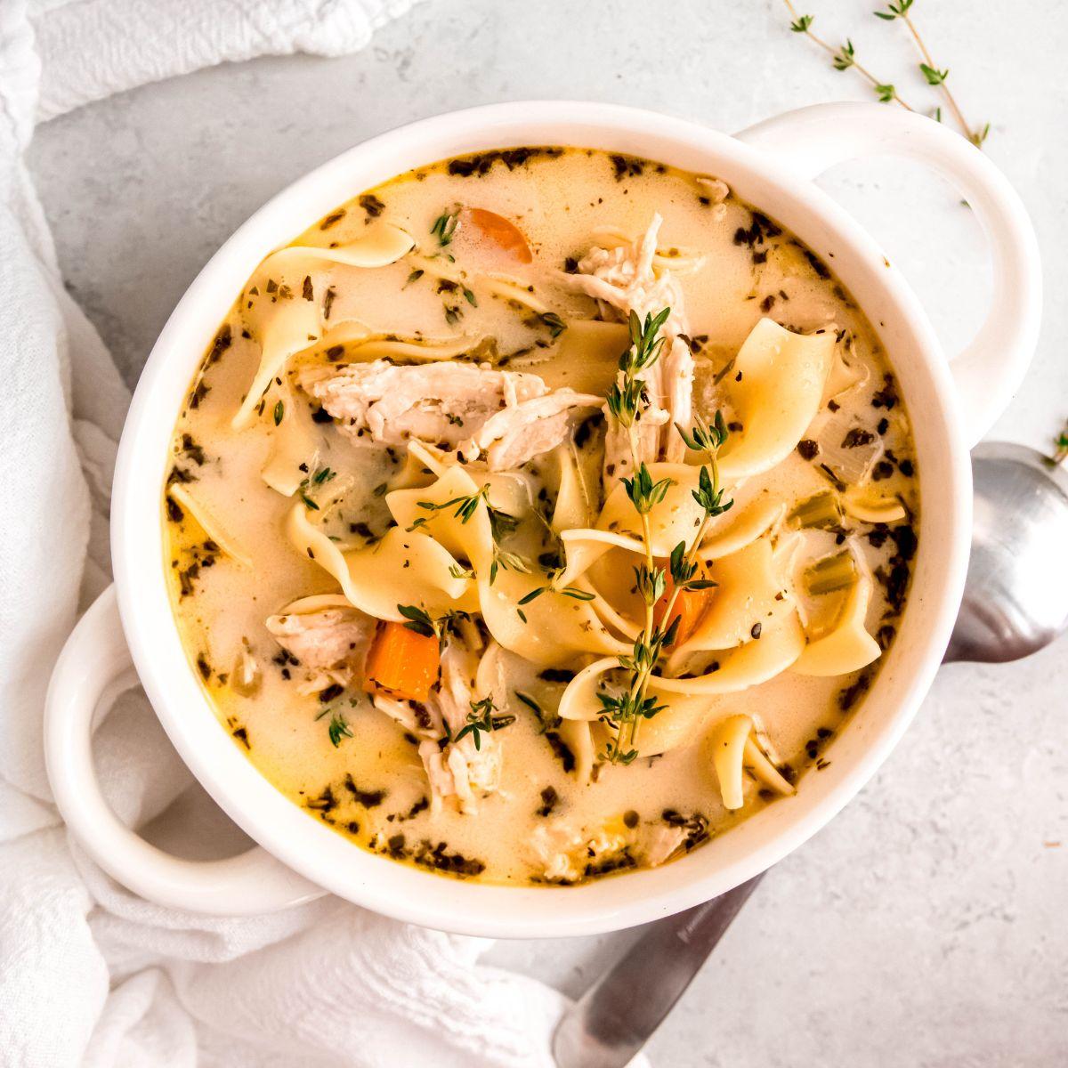 A steaming bowl of creamy turkey noodle soup garnished with fresh parsley