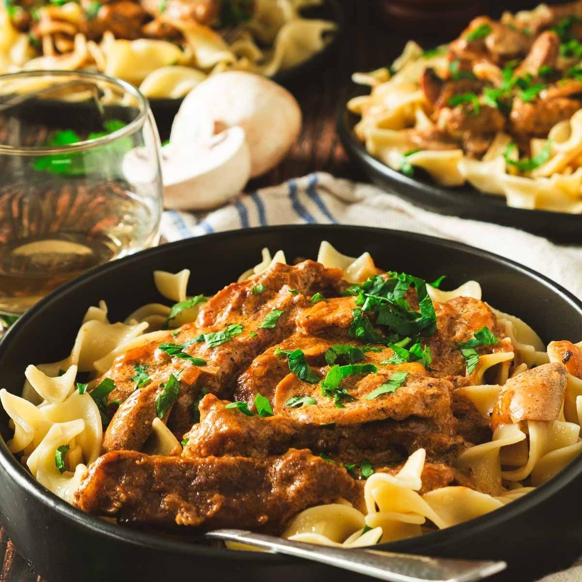 Beef stroganoff served over egg noodles, garnished with fresh parsley
