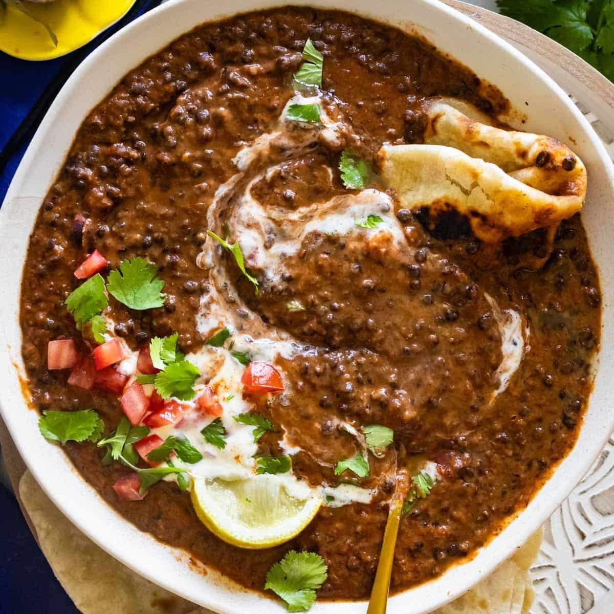 A table setting with a bowl of smoky eggplant black urad dal, rice, and naan bread