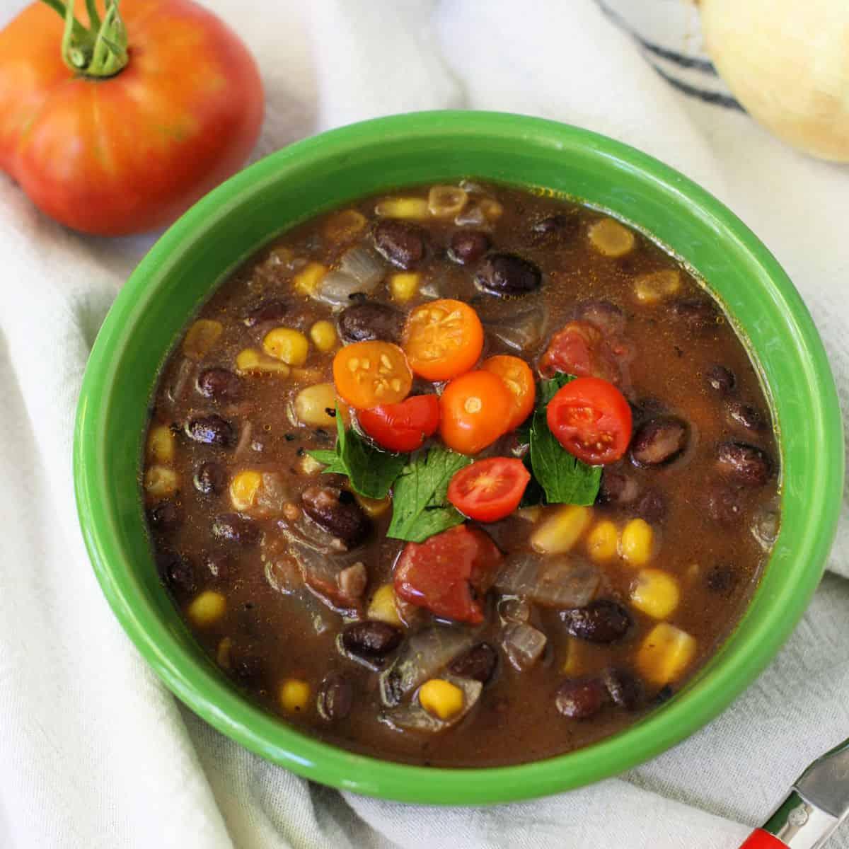 A pot of vegan corn and black bean soup simmering on the stove