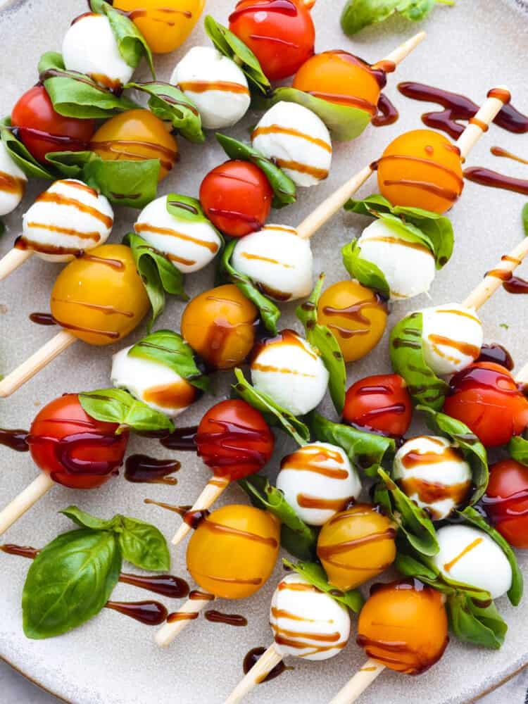 balsamic reduction being drizzled over Caprese salad skewers