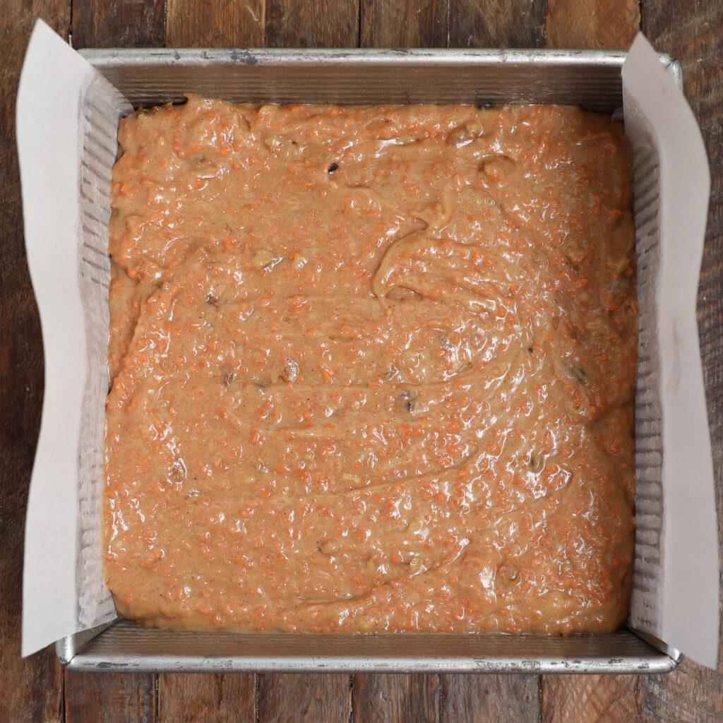 A close-up shot of the carrot cake brownie batter being poured into the baking pan