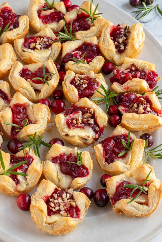 a person grabbing a cranberry brie bite from a platter