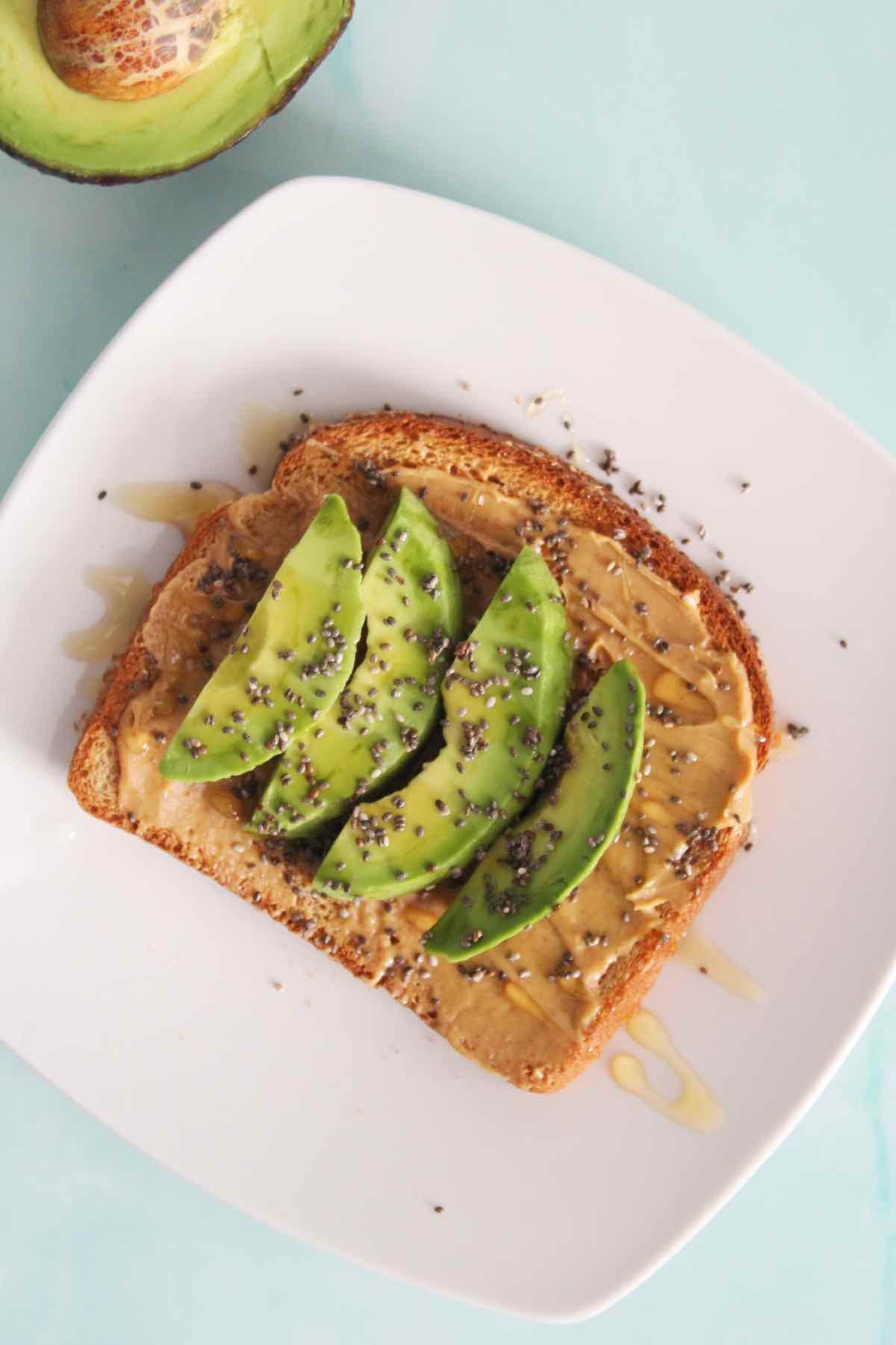 Person enjoying a slice of avocado toast with peanut butter