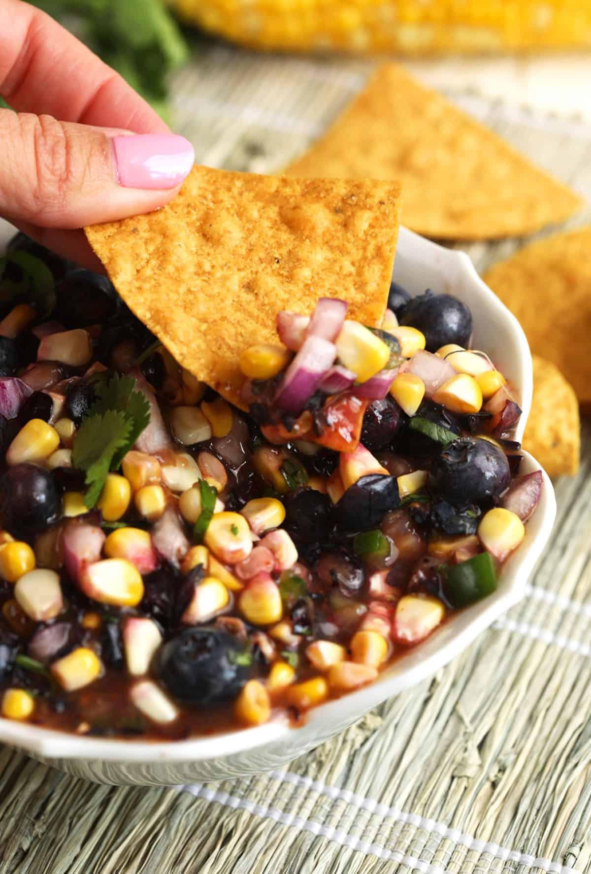 Grilled corn and blueberry salsa in a bowl with tortilla chips