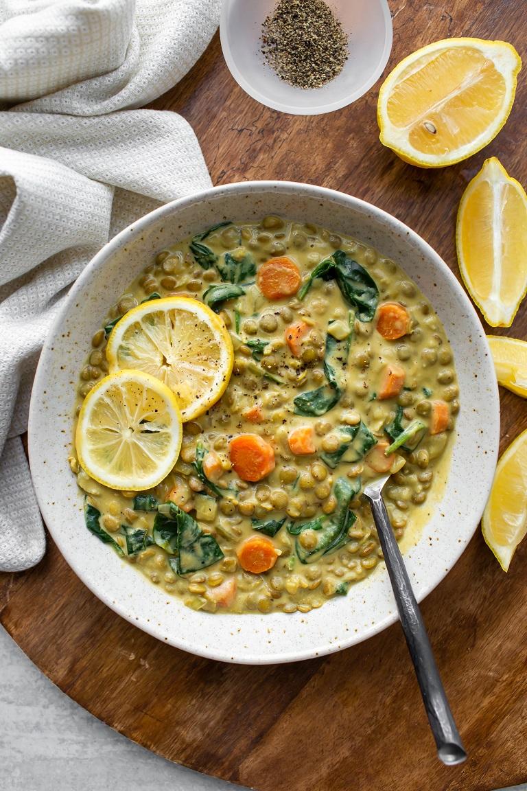 Creamy vegan lentil soup with lemon and herbs in a rustic bowl