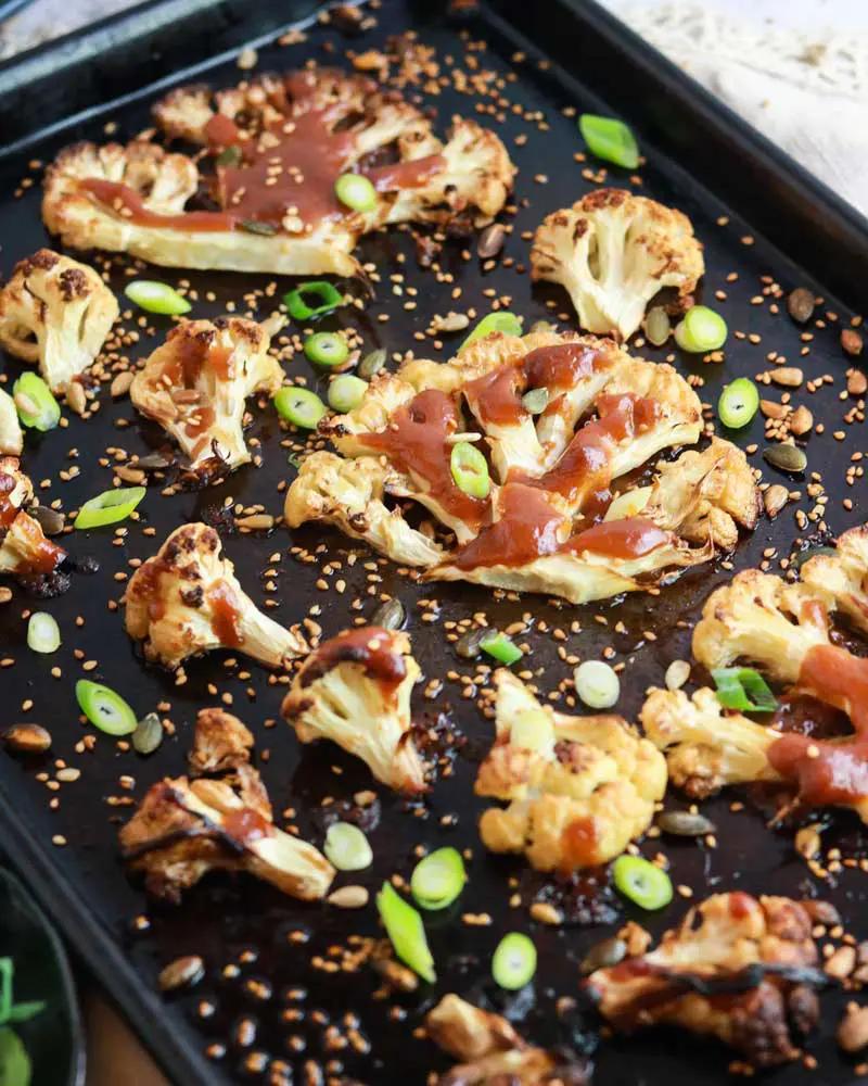 roasted miso-glazed cauliflower steak on a plate with sesame seeds