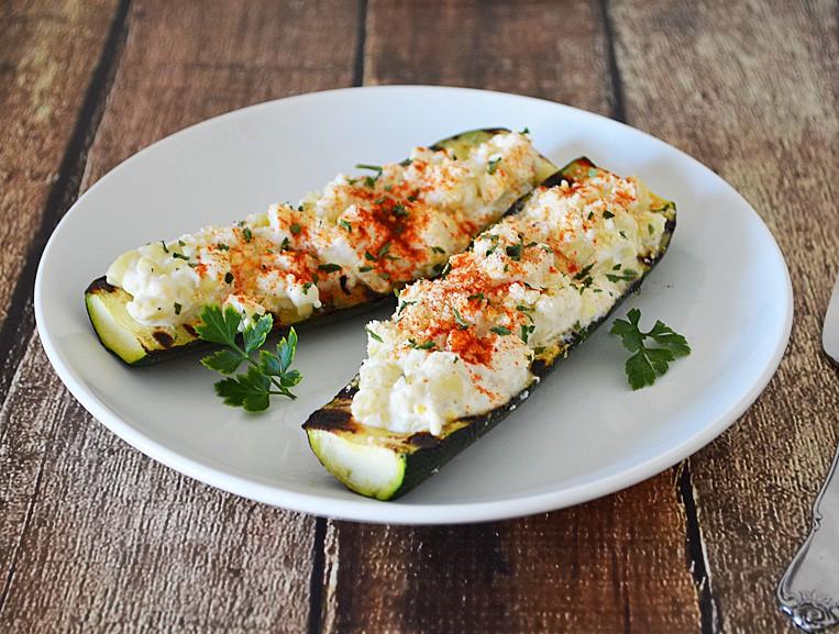 Grilled corn and zucchini boats served on a rustic wooden table