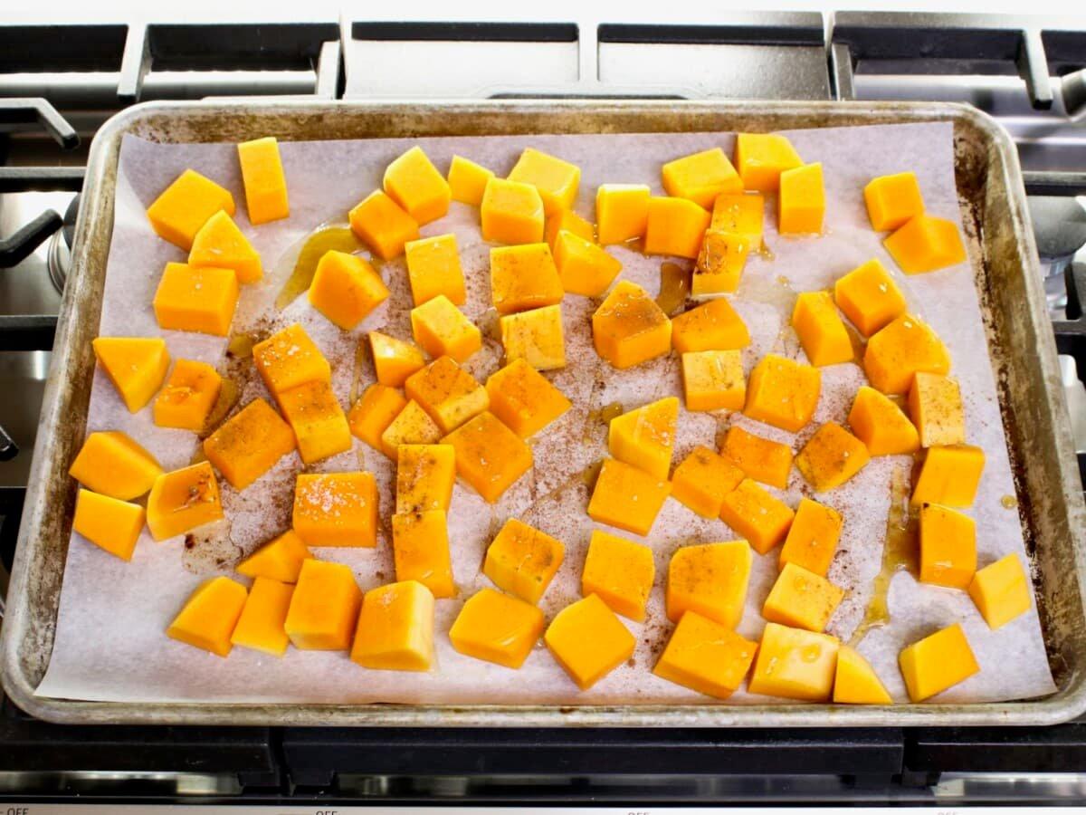overhead shot of roasting butternut squash cubes on a baking sheet