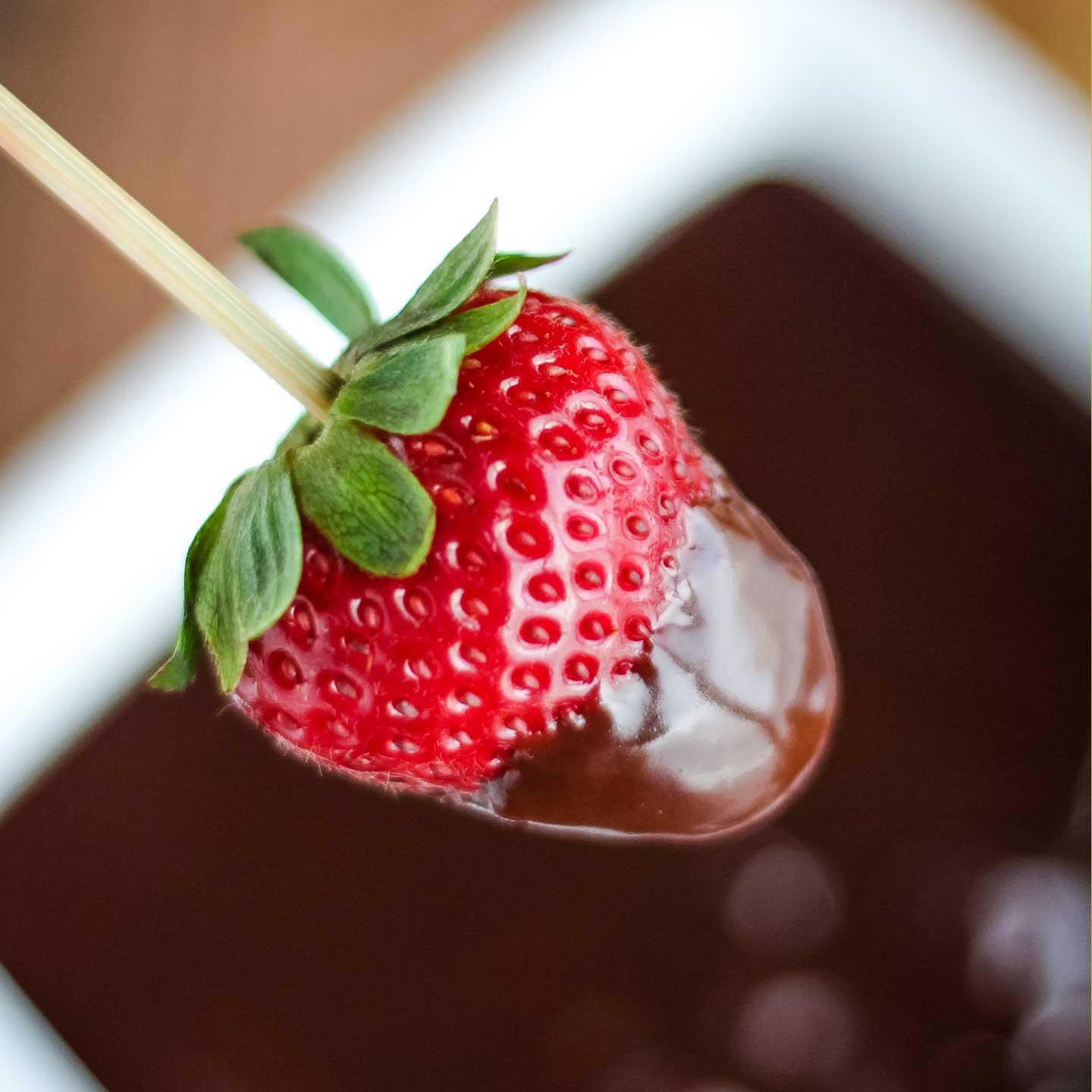 close-up shot of chocolate fondue with a strawberry being dipped