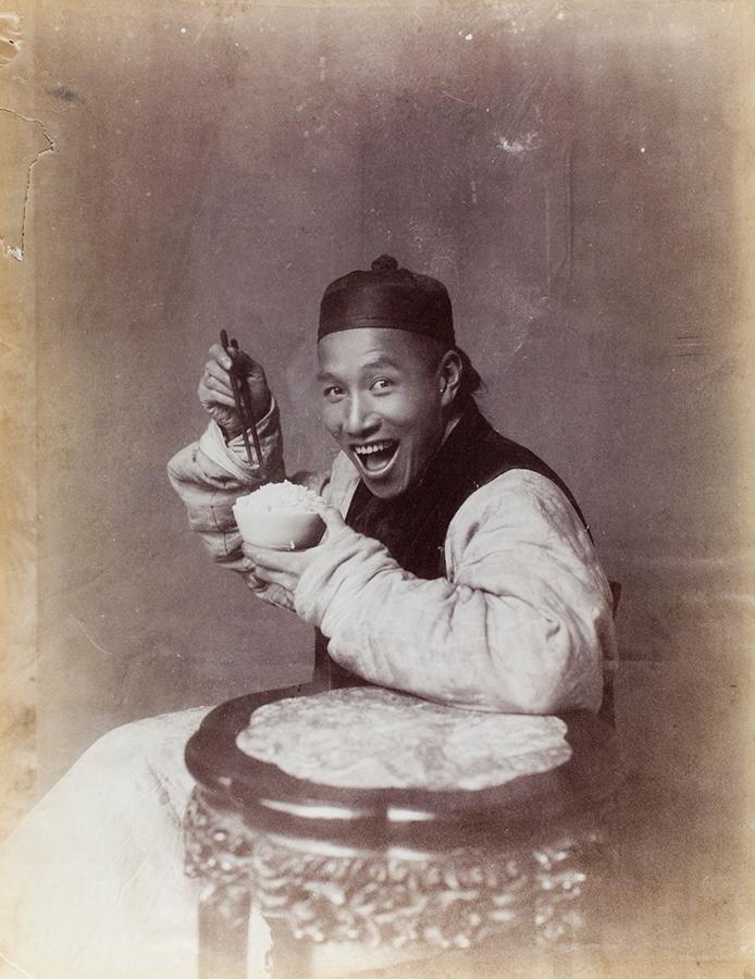 A person enjoying a black rice bowl outdoors, smiling and holding the bowl