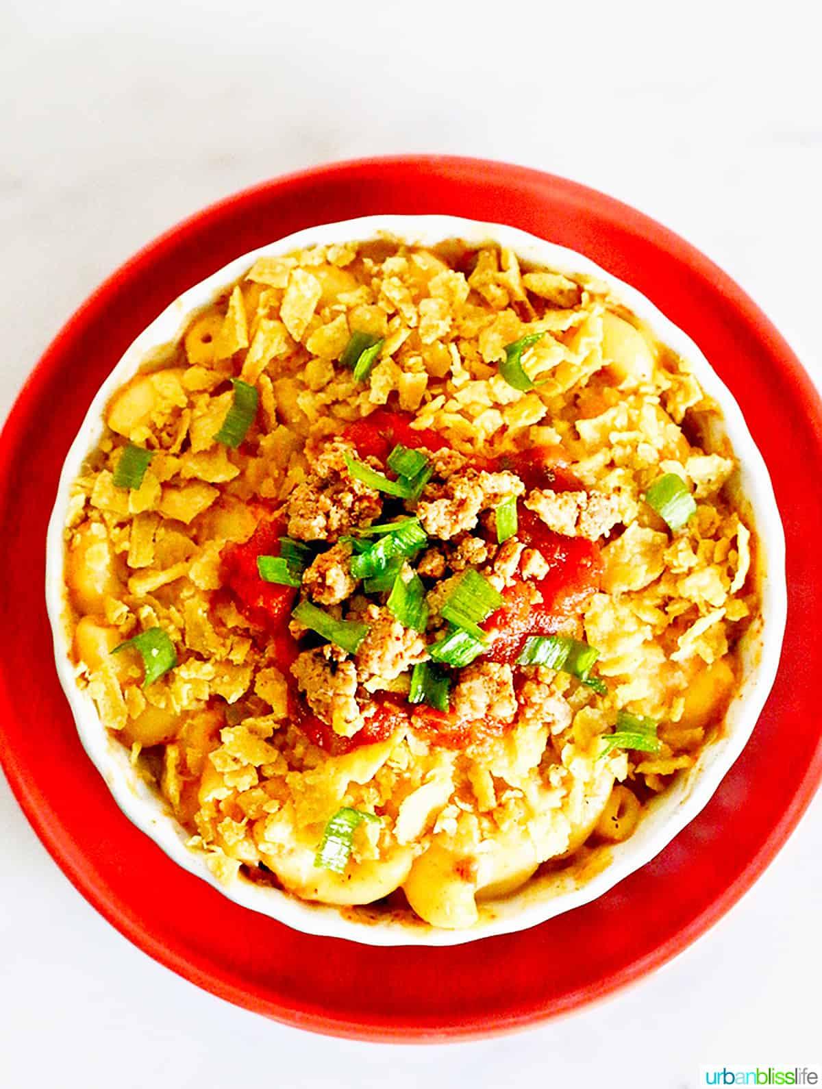 A golden-brown 9x13 inch baking dish filled with Taco Mac and Cheese, garnished with fresh cilantro and diced tomatoes.