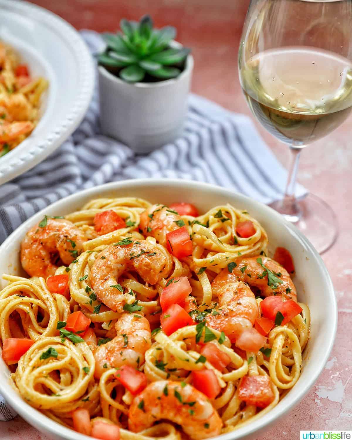 Cajun shrimp pasta served in a rustic bowl with a glass of white wine