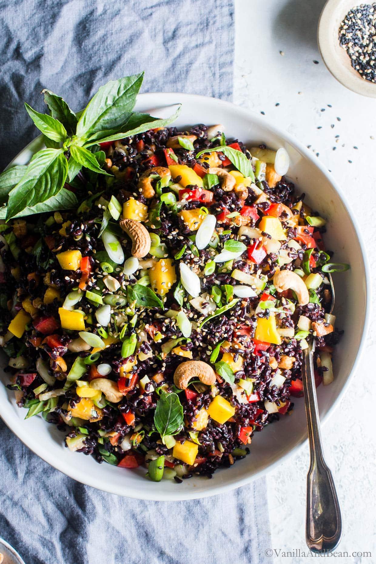 A vibrant bowl of Forbidden Rice Pasta Salad with Mango and Coconut on a picnic table