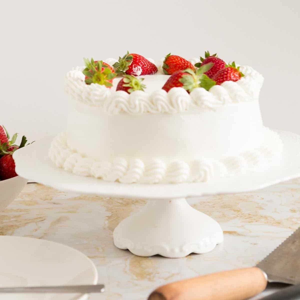 A perfectly frosted genoise cake on a cake stand