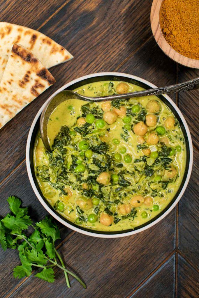overhead shot of a pot of chickpea and green bean curry simmering on a stove