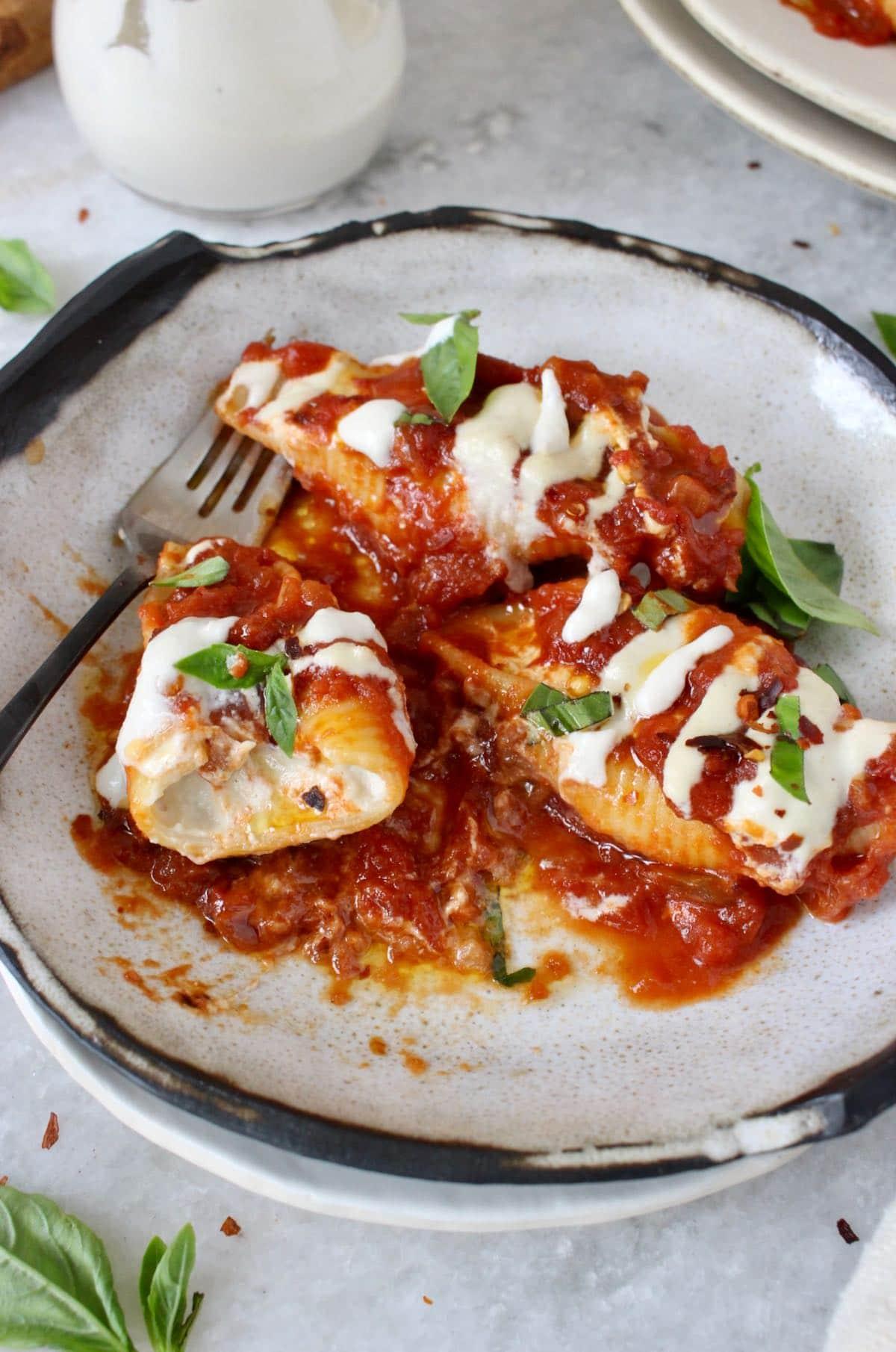 Close-up shot of a delicious plate of vegan cheese stuffed shells, with a creamy cashew cheese sauce drizzled on top.