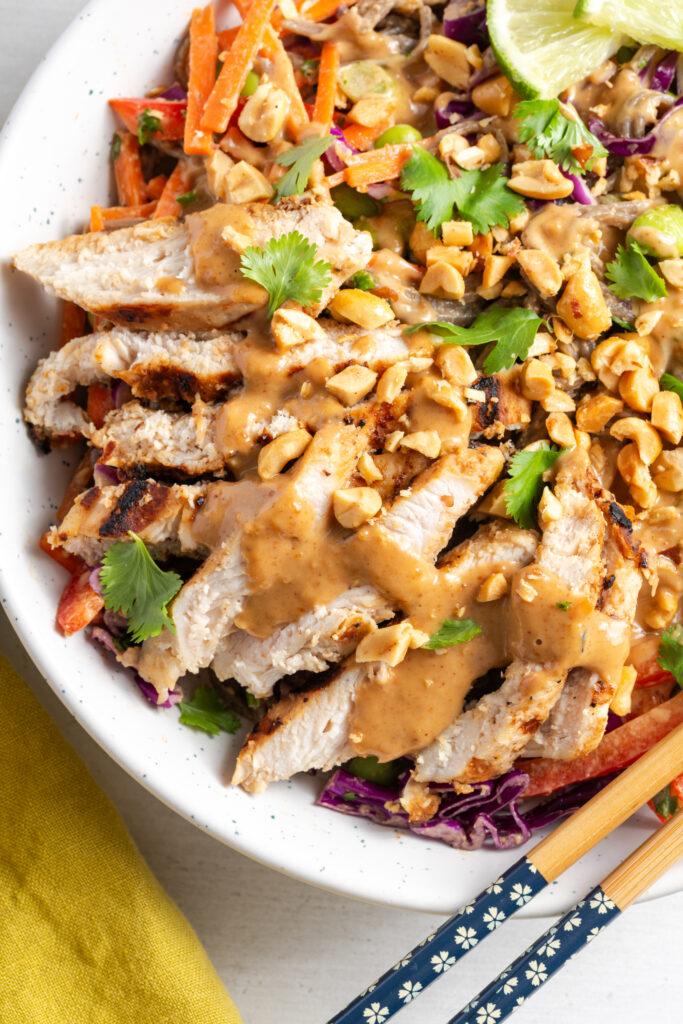 Overhead shot of a vibrant Thai peanut noodle grain bowl with chicken