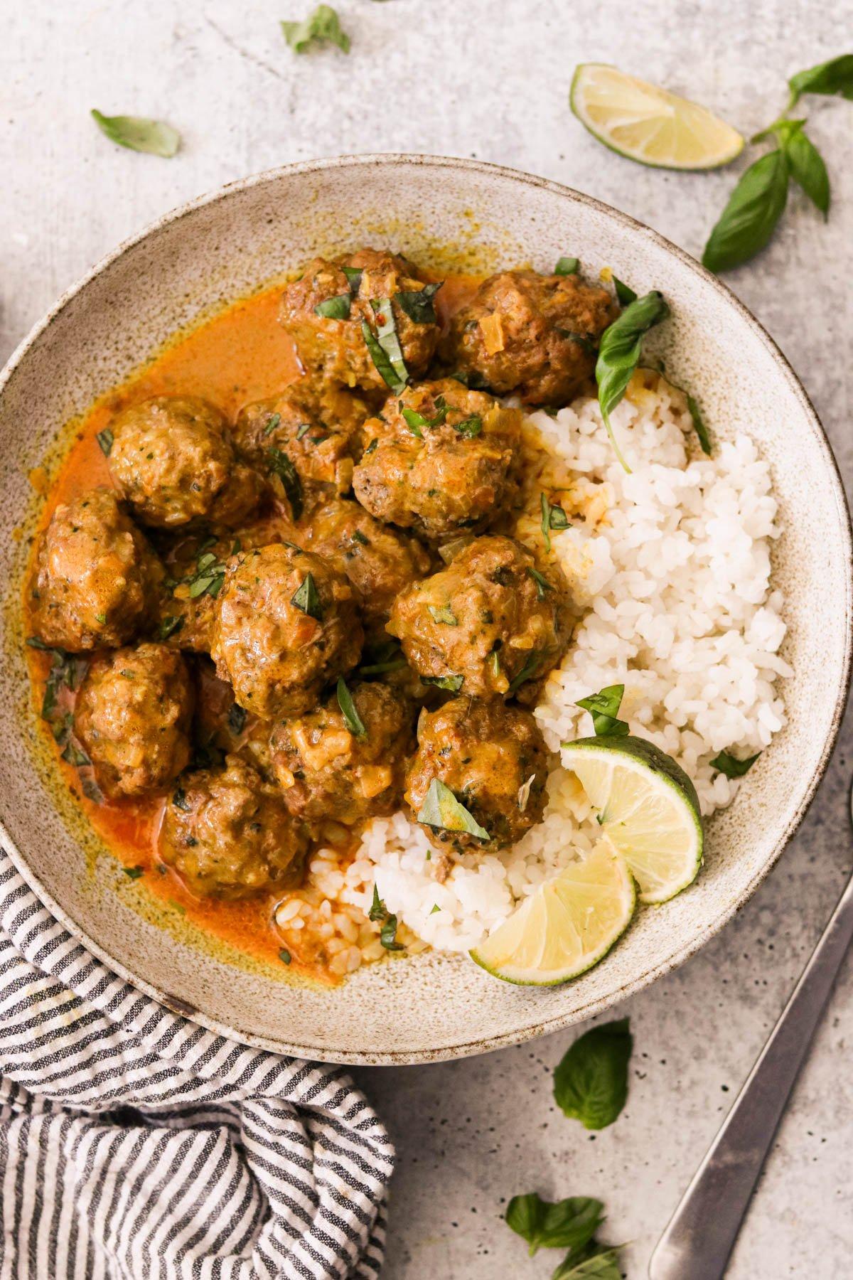 a bowl of curried coconut plant-based meatballs with rice being served