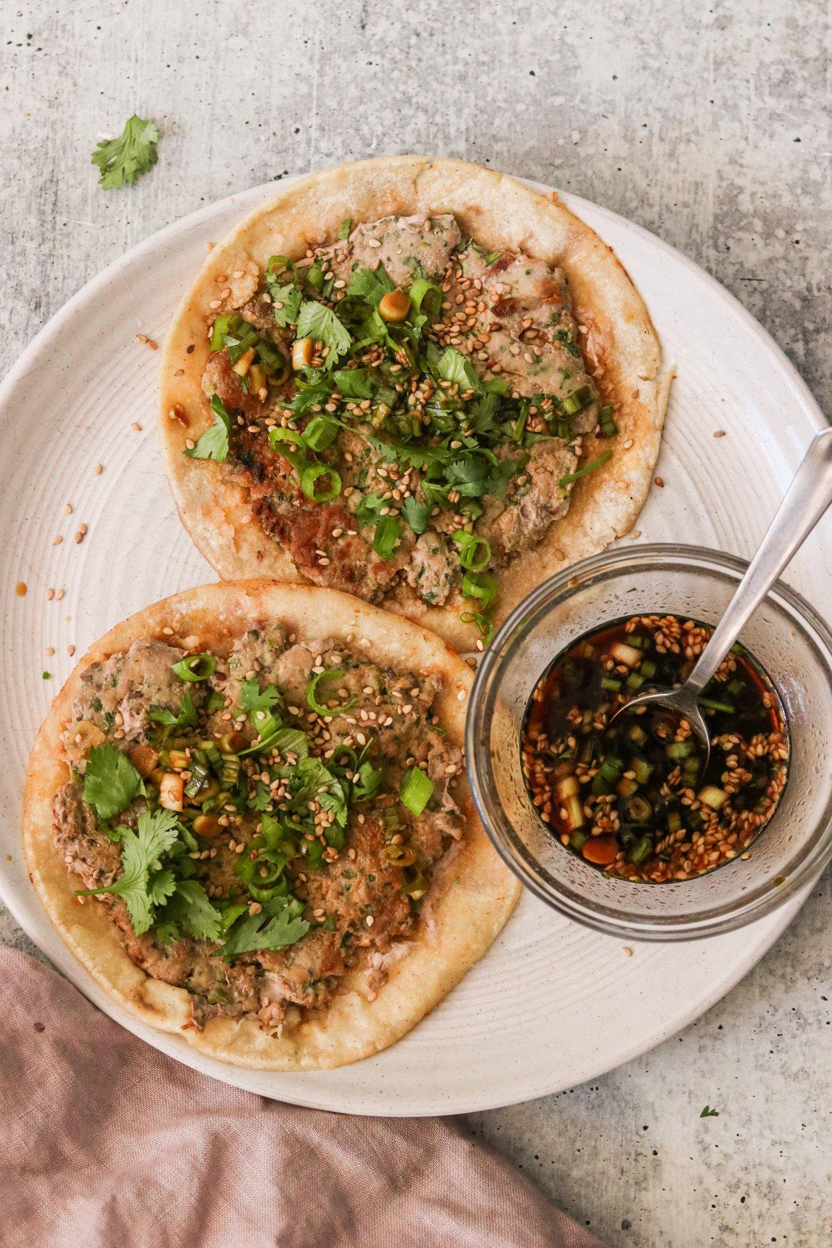 Kimchi dumplings in crispy taco shells, garnished with fresh cilantro and sesame seeds