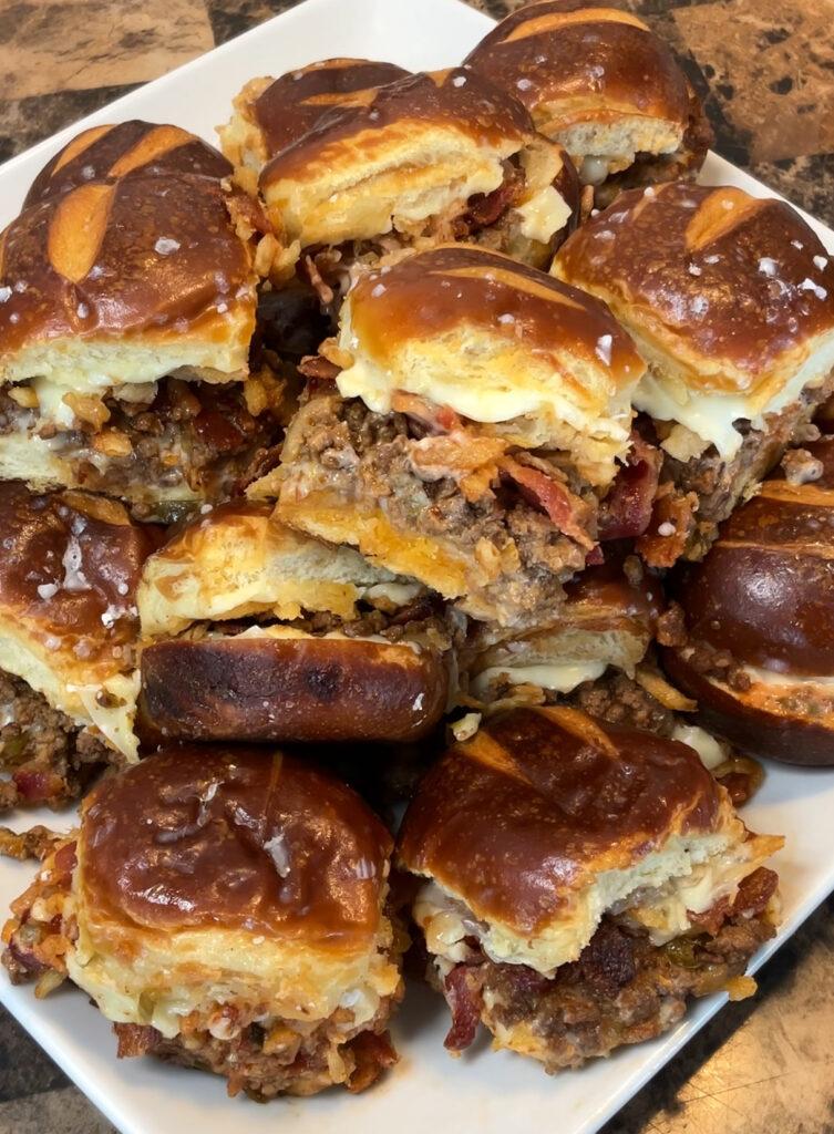 Close-up shot of bacon cheddar beer pretzel sliders on a baking sheet