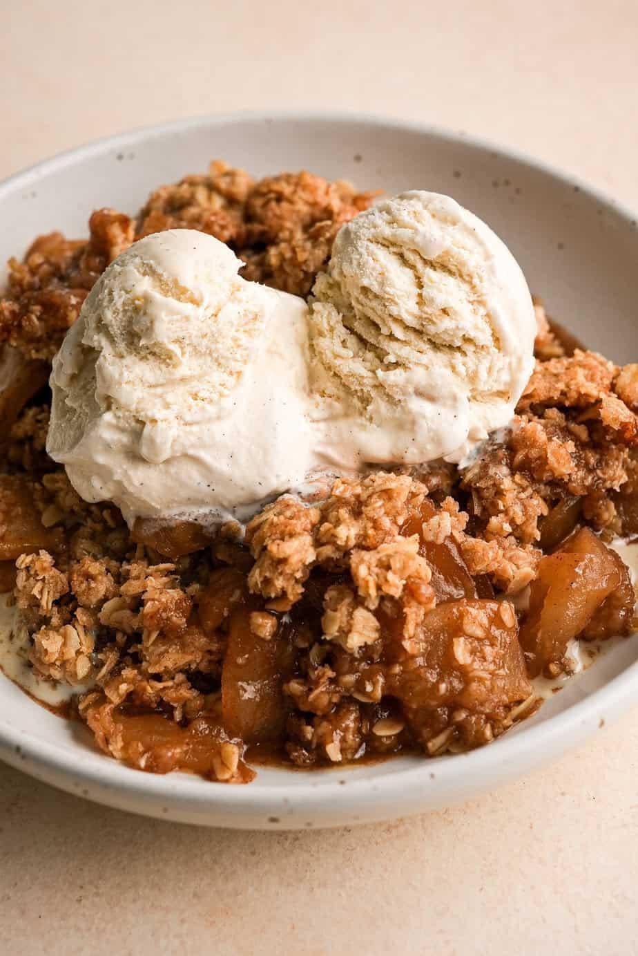 close-up of a spoonful of apple crisp with caramel and vanilla ice cream