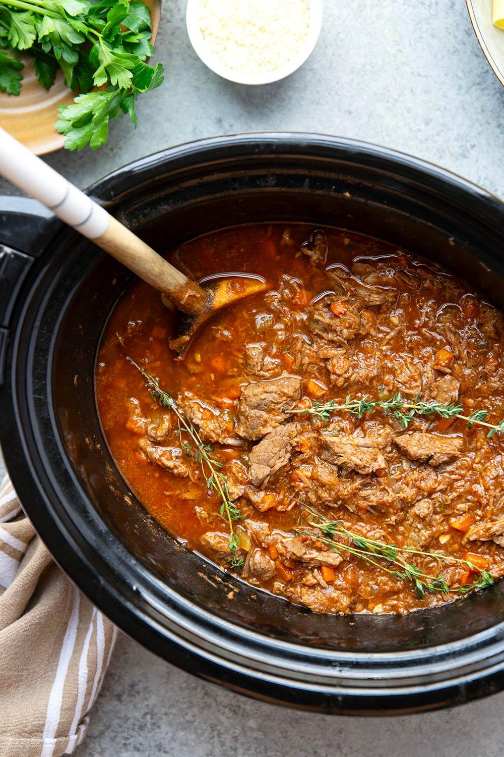 Close-up shot of a bubbling beef ragu simmering in a Dutch oven