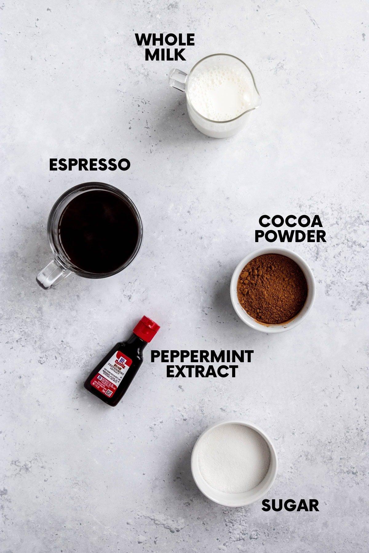 Ingredients for peppermint mocha laid out: cocoa powder, peppermint extract, coffee, milk, sugar