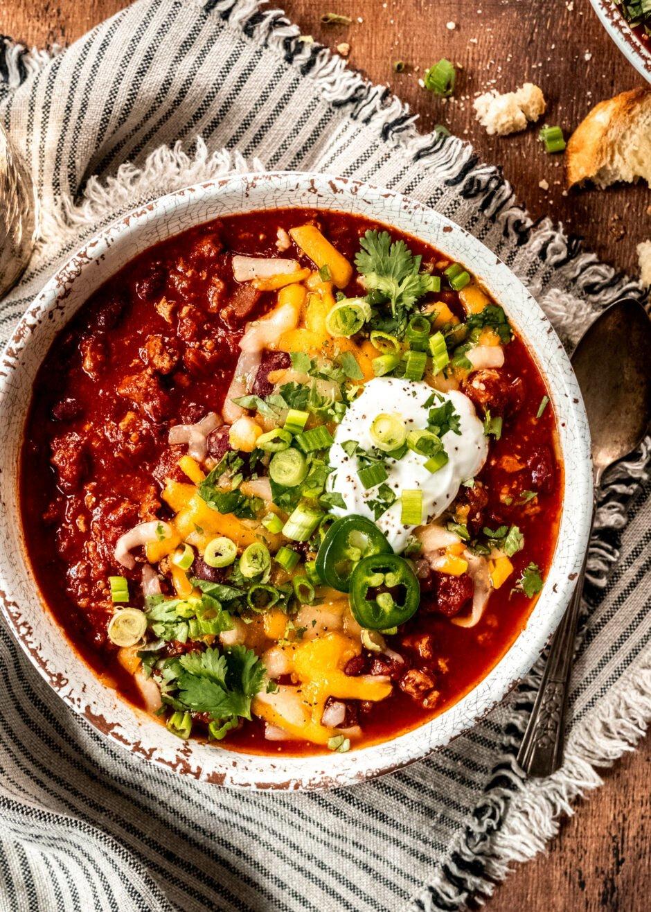 A hearty bowl of turkey and vegetable chili, garnished with fresh cilantro and a dollop of sour cream, ready to be served.