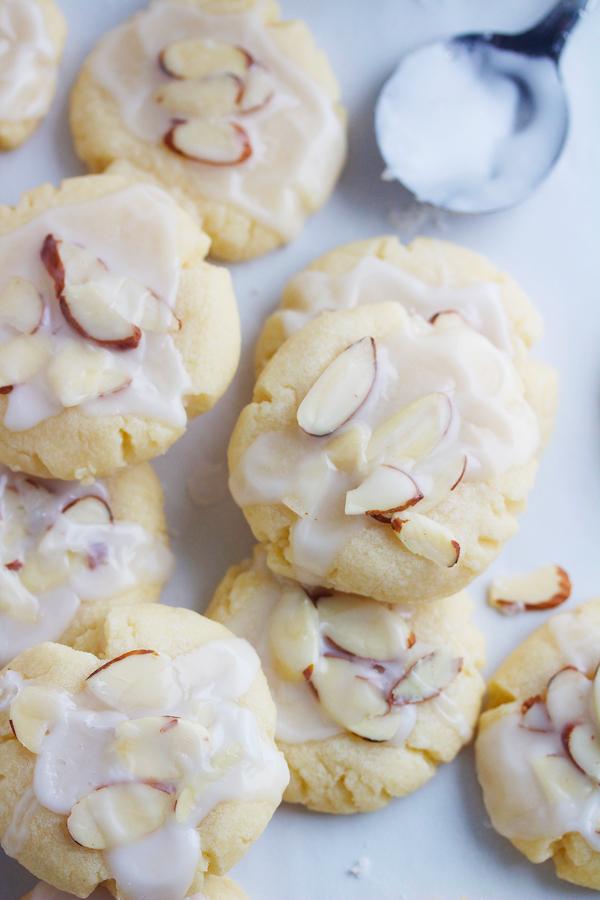close-up of a hand piping glaze onto an almond cookie with delicate patterns