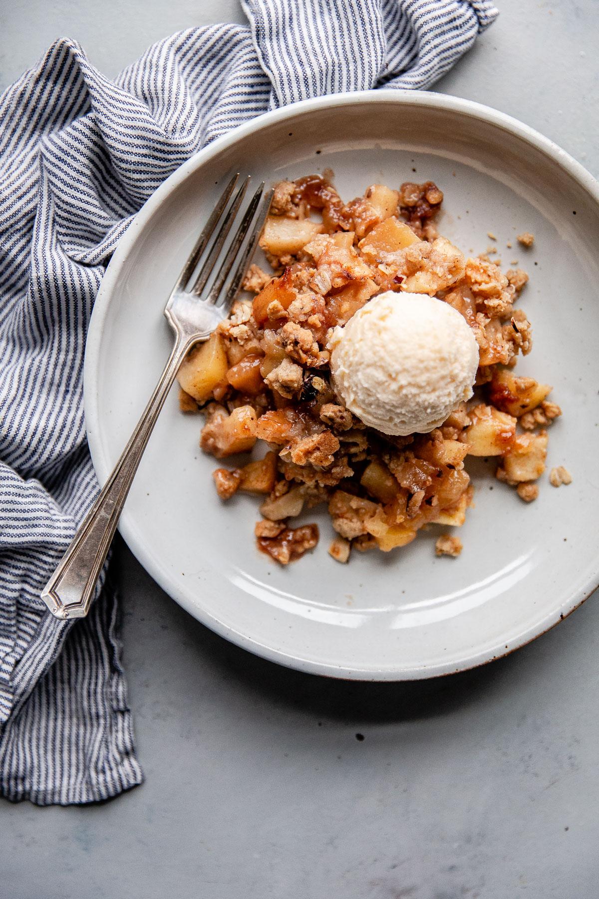 Close-up shot of a warm apple crisp with a golden brown hazelnut topping, steam rising