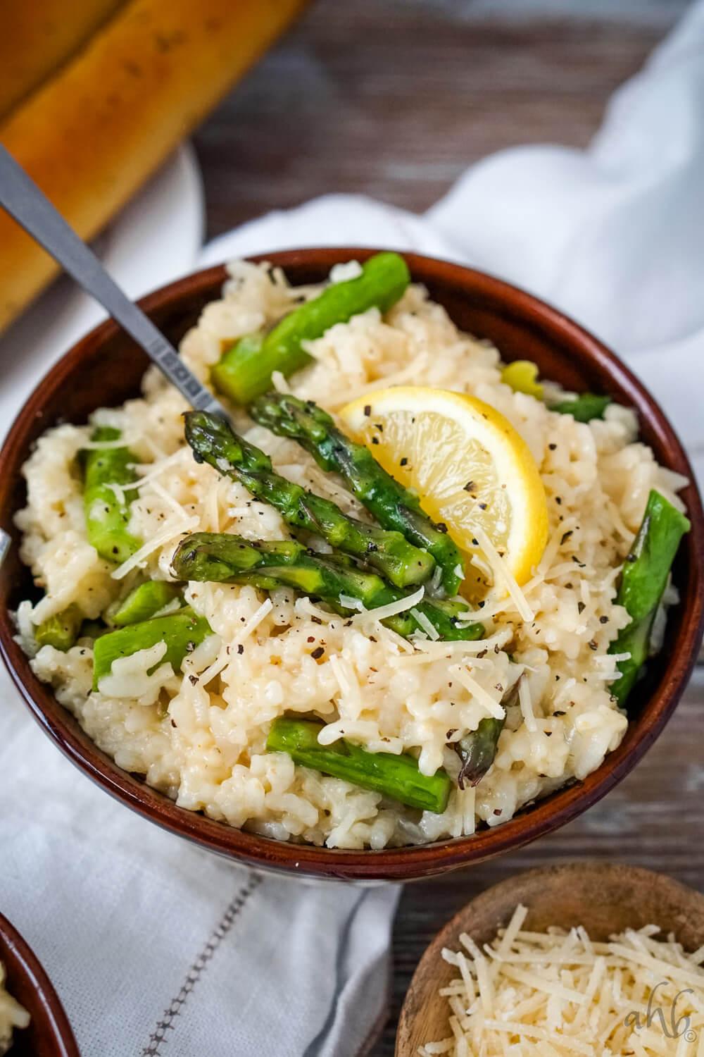 A vibrant and delicious bowl of Asparagus Risotto with Wild Rice, garnished with fresh herbs and parmesan cheese, shot with a shallow depth of field.